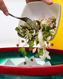 Food being scraped from a plate into a trash can