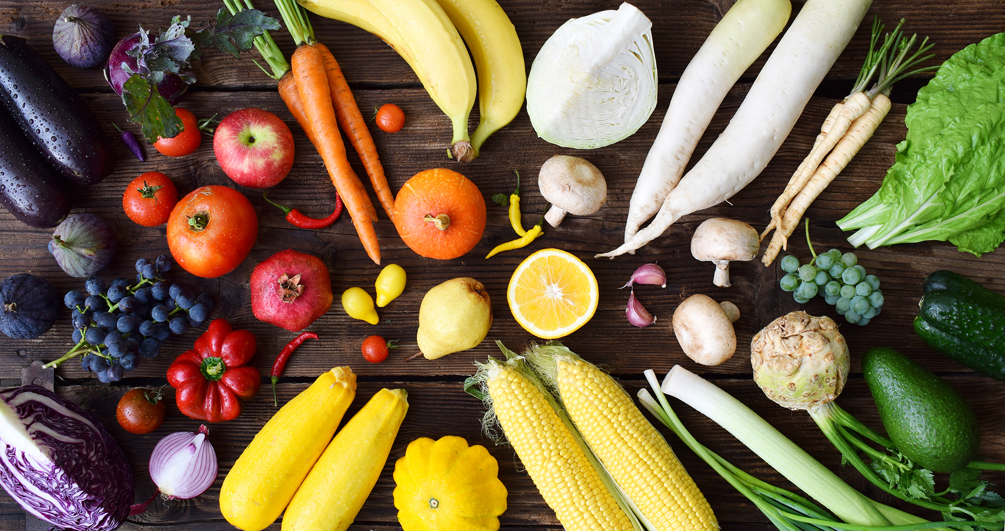 White, yellow, green, orange, red, purple fruits and vegetables on wooden background. 
