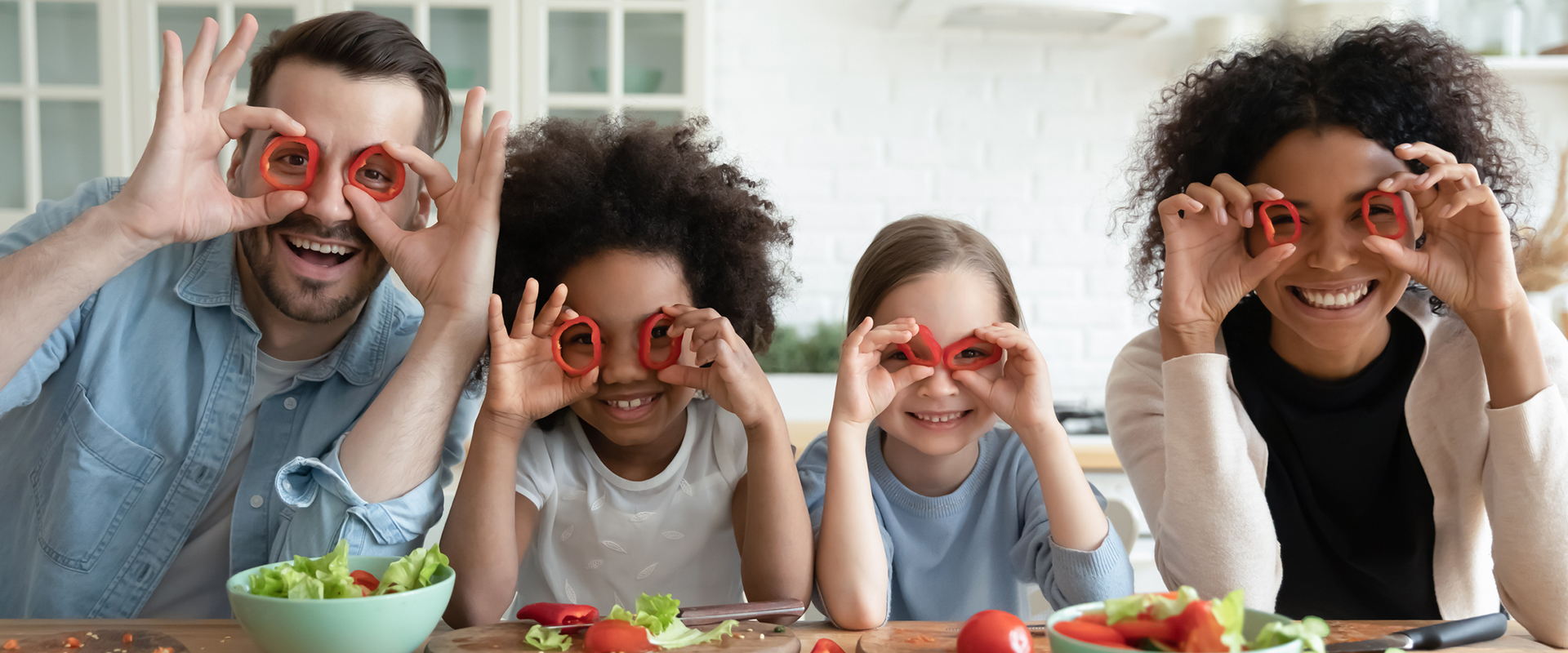 A man, woman and two kids holding red pepper rings up to their eyes 