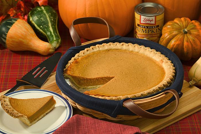 Canned pumpkin and fresh pumpkins next to a pumpkin pie with a slice on a plate