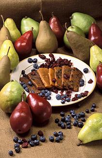 Pear fruit bars on a plate surrounded by pears, blueberries and cranberries. 