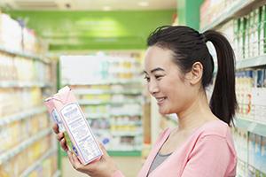 A young Asian woman reading a Nutrition Facts label 