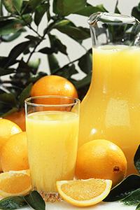 K7237 8 A glass of orange juice, a pitcher of orange juice and fresh oranges
