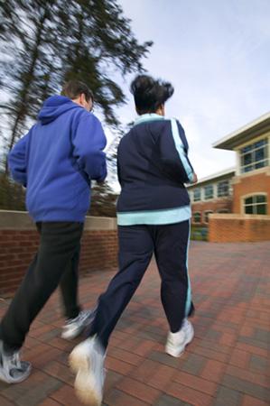 A man and a woman in athletic clothing taking a fast-paced walk 