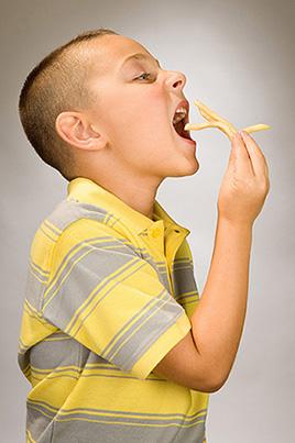 A boy eating French fries