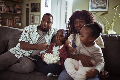 A family watching a movie at home and eating popcorn.