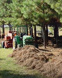 Farm equipment moving along a tree line. 