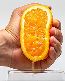 A hand squeezing half of an orange. 