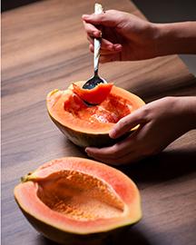 A person eating a papaya with a spoon.