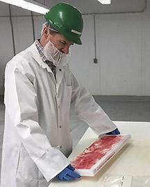 A scientist holding a tray of beef