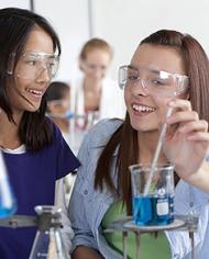 Female high school students performing experiment in chemistry lab