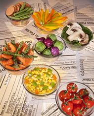 Bowls of fruits and vegetables arranged on top of nutrition labels