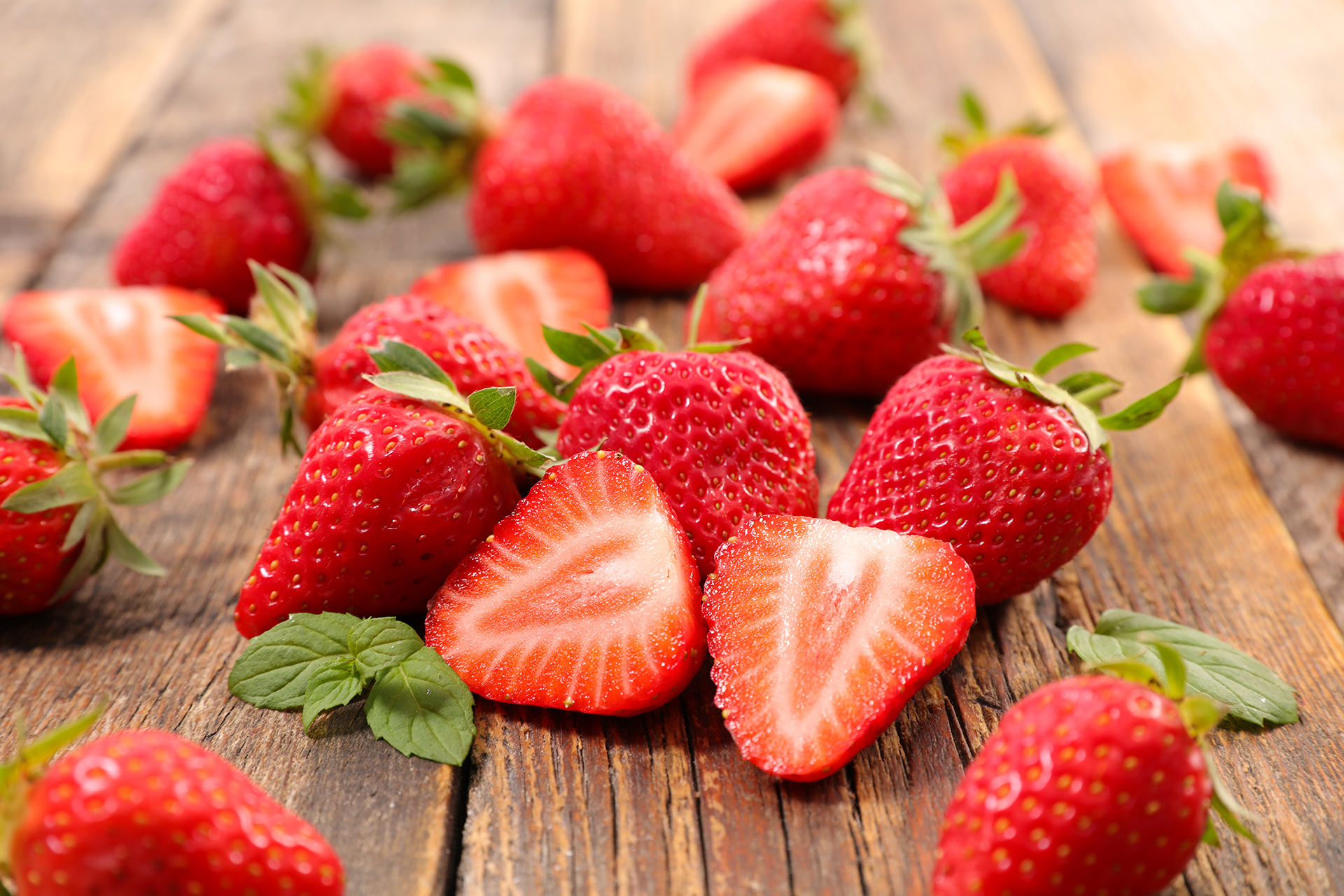 Sliced fresh strawberries laying on a wooden board