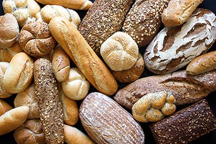 BreadWaste Many mixed breads and rolls shot from above.