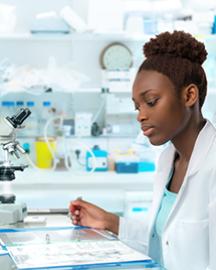 Woman in a white lab coat looking at a document in a laboratory